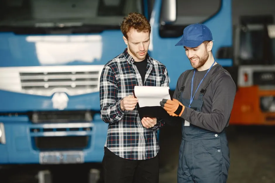 Illustrative photo of commercial drivers reviewing paperwork beside a truck